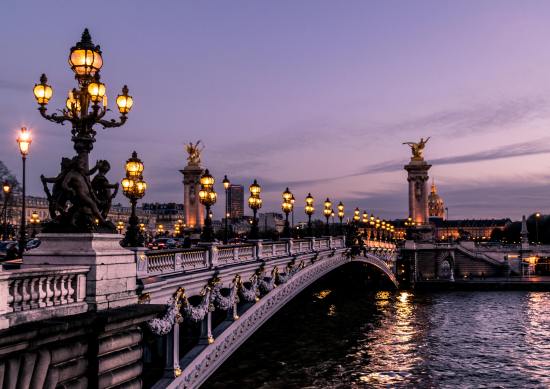 Image of a bridge in Paris at night, lit up.