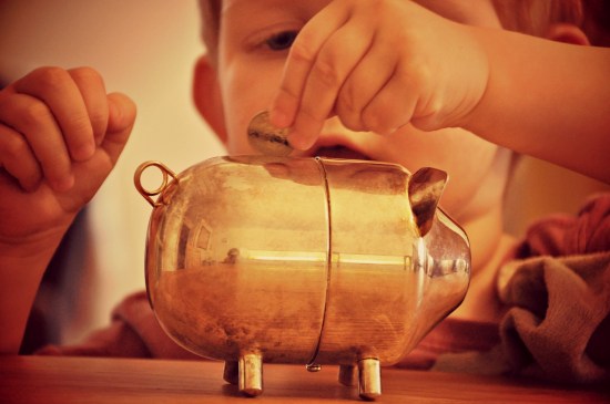 refilling piggy bank child putting coins in piggy bank
