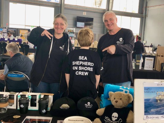 Three people in Sea Shepherd t-shirts standing at a stall selling merchandise