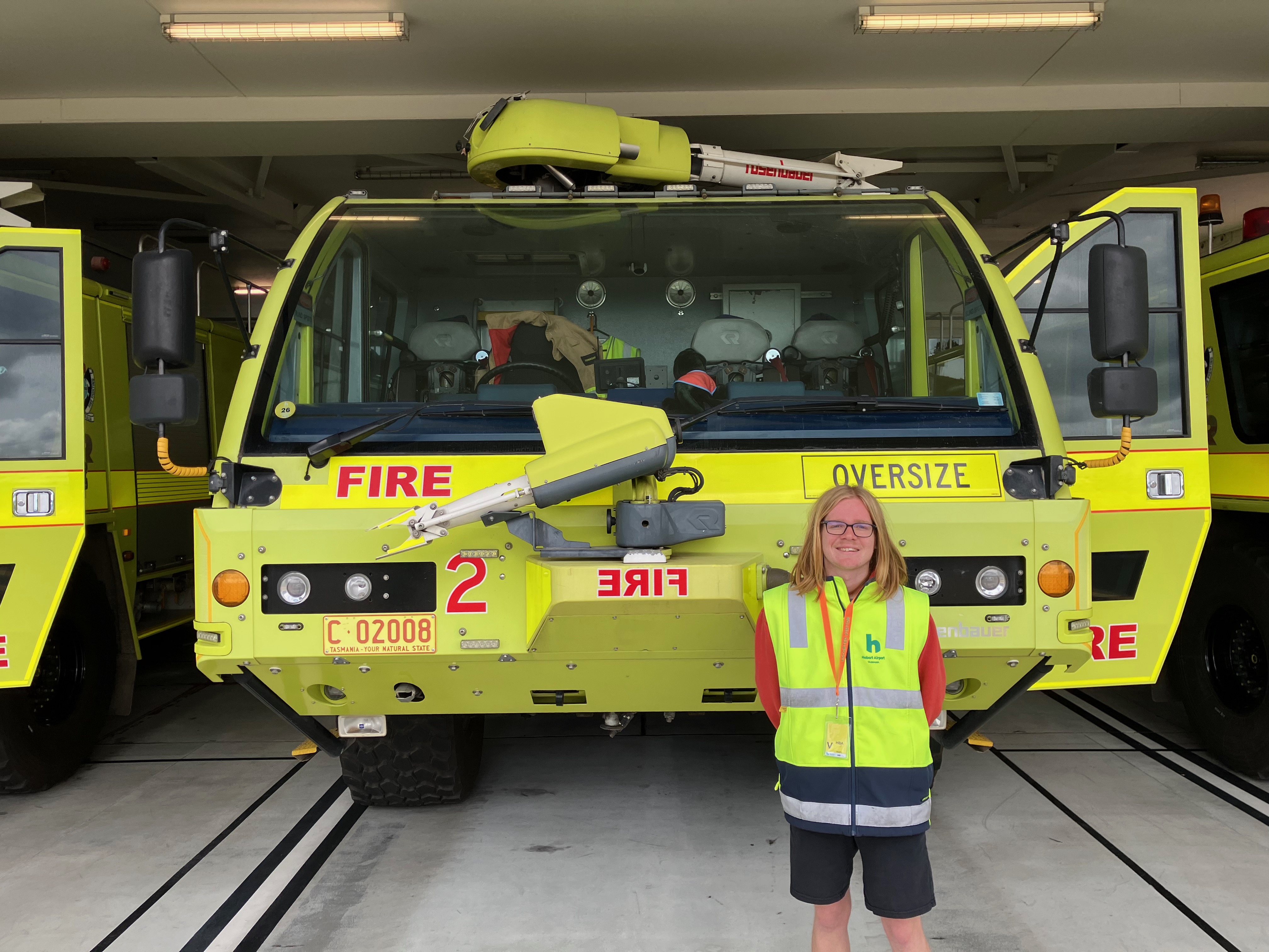 Work experience student standing in front of Hobart Airport fire truck